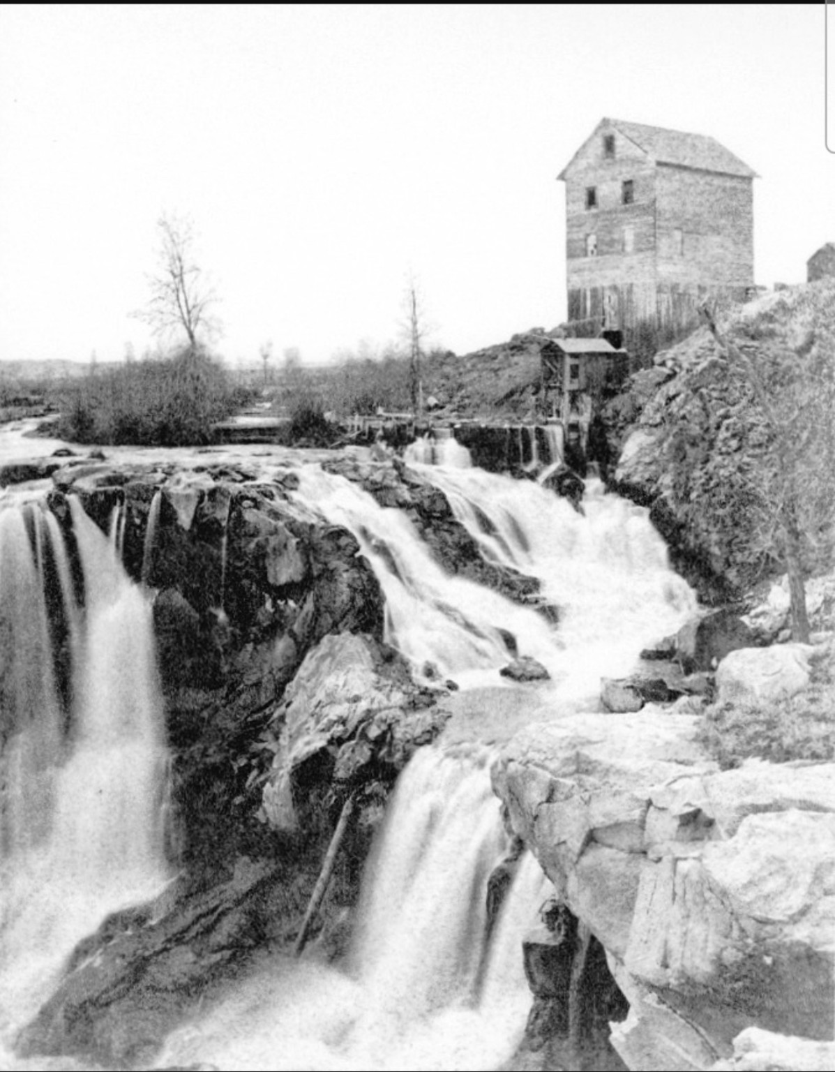 Historic black-and-white view of White River Falls and the early waterworks above the gorge